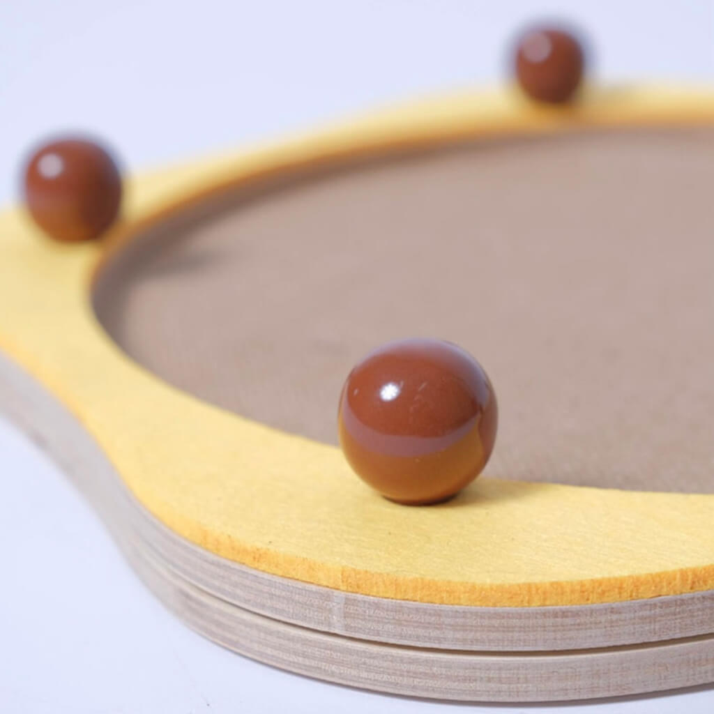 Close-up of brown ceramic decorative balls on yellow Sisal Cat Scratcher Panel with wooden base.