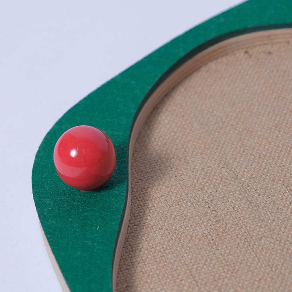 Close-up of red ceramic decorative ball on green Sisal Cat Scratcher Panel with wooden base.