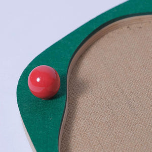 Close-up of red ceramic decorative ball on green Sisal Cat Scratcher Panel with wooden base.