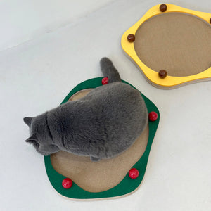 Cat playing on green Sisal Cat Scratcher Panel with red ceramic decorative balls next to a yellow version.