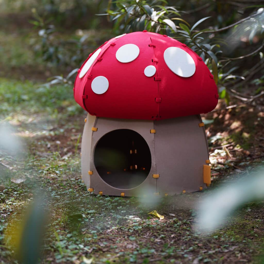 Mushroom Felt Cat Cave placed outdoors in a garden, highlighting its playful design.