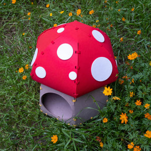 Overhead view of the Mushroom Felt Cat Cave in a flower field, emphasizing its unique mushroom design.