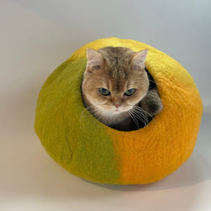 Side view of cat entering Amalfi Lemon wool felt cave; modern enclosed cat bed in lemon yellow with green accent.