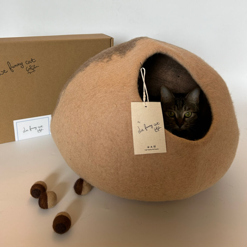 Cat peeking from Beige Mochi wool felt cat cave with box and felt toys — handmade enclosed cat house.