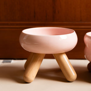 Side view of cherry pink ceramic pet food bowls with sturdy wooden legs.