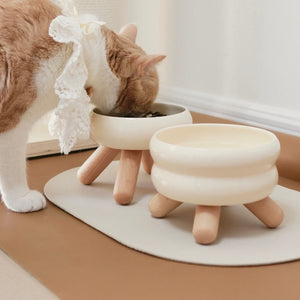 Gulu Ceramic Pet Bowl - Cream White in a bright, modern home interior with wooden legs.