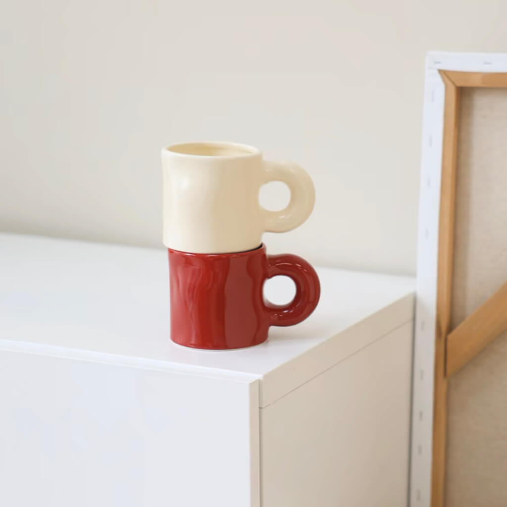 Stacked Pinch Ceramic Mugs – Cream White and Bordeaux Red – A stylish display of stacked Pinch ceramic mugs in cream white and Bordeaux red, showing their modern design and unique handles.