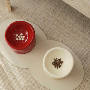 Pinch Ceramic Pet Bowls – Bordeaux Red and Cream White – A close-up of two Pinch ceramic pet bowls, one in Bordeaux red and the other in cream white, filled with treats, highlighting their elegant design.