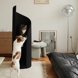 Modern black Meoof Time Travel Cat Tower with a curious Jack Russell dog reaching up to a tabby cat resting inside. Stylish pet furniture for multi-pet households.