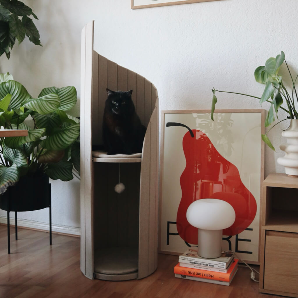 Black cat lounging on Meoof Time Travel Tower Cat Tree in oatmeal color – stylish space-saving cat furniture for climbing and relaxation.