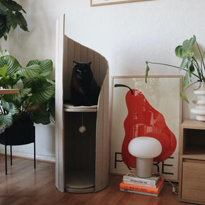 Black cat lounging on Meoof Time Travel Tower Cat Tree in oatmeal color – stylish space-saving cat furniture for climbing and relaxation.