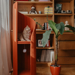 Time Travel Tower Cat Tree in Red, featuring a modern spiral design and cozy perch, blending seamlessly into a stylish living space with a bookshelf and greenery.
