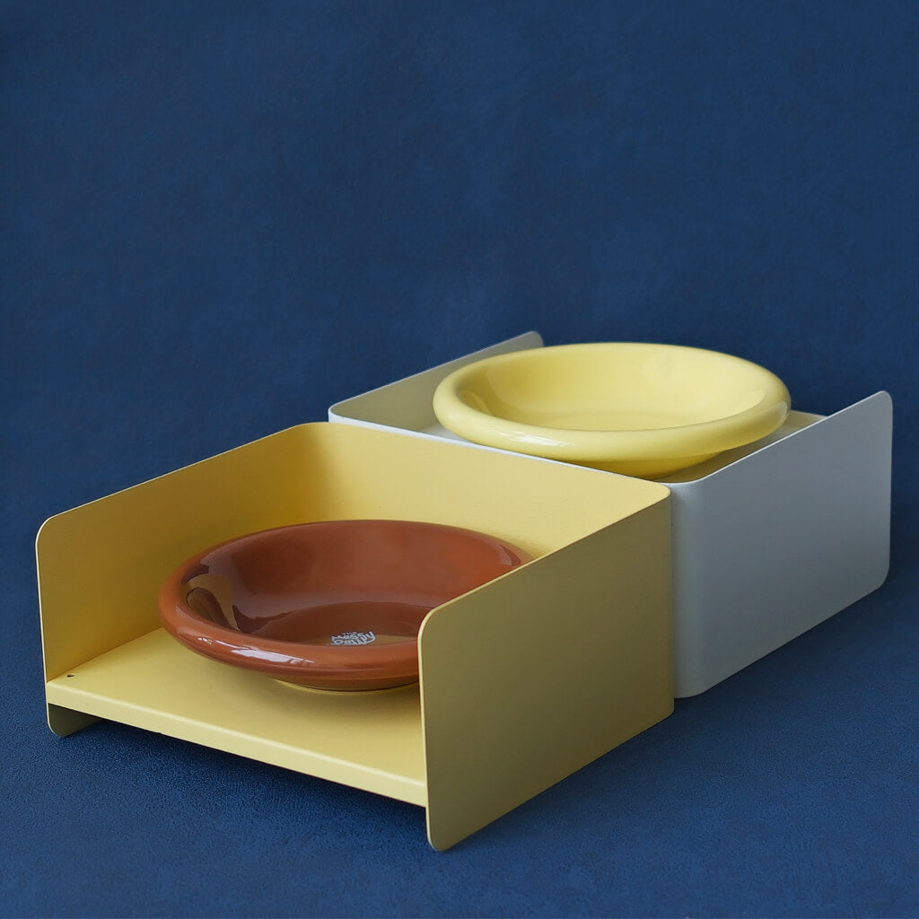 Adjustable yellow and white elevated pet feeders holding ceramic dishes – metal dual-height bowl stands for modern pet homes.