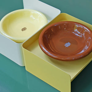 Close-up of yellow and white metal pet bowl stands with brown and yellow ceramic dishes – minimalist elevated pet feeders.