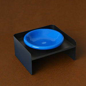 Black metal dual-height pet bowl stand with bright blue ceramic dish – minimalist feeding solution for small pets.