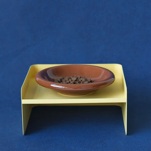 Yellow metal elevated pet feeder with brown ceramic dish – modern dual-height design for cats and dogs.