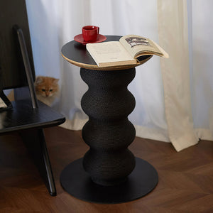 Modern side table cat scratcher styled with red cup and open book, ginger cat peeking from behind curtain.