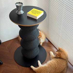Three cats relaxing and playing around sculptural cat scratcher table placed near window blinds.