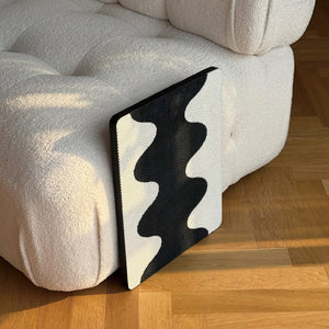 Coral Cat Scratching Pad with sleek black-and-white wave pattern leaning against cream sofa