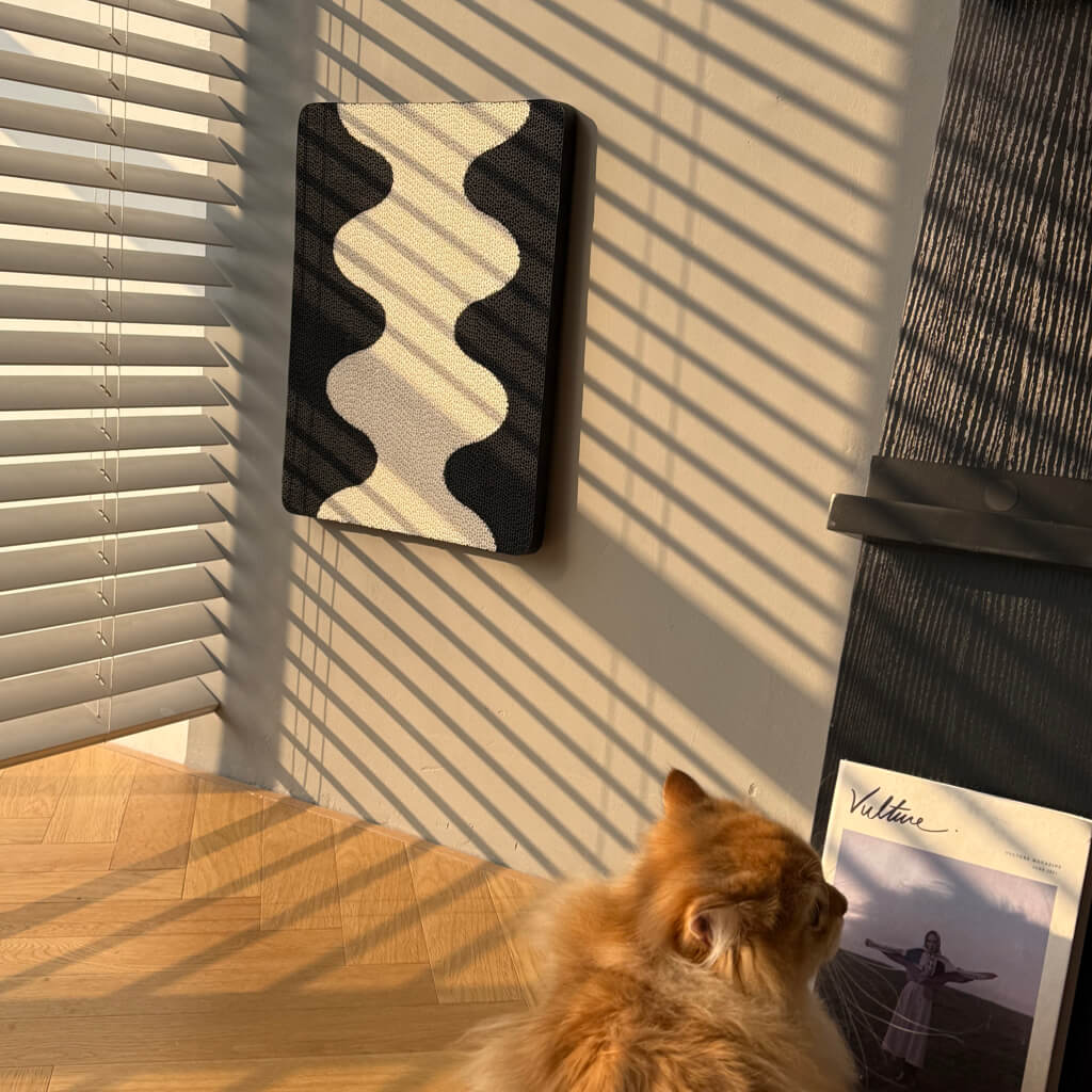 Coral Cat Scratching Pad mounted on wall in sunlight with fluffy orange cat nearby