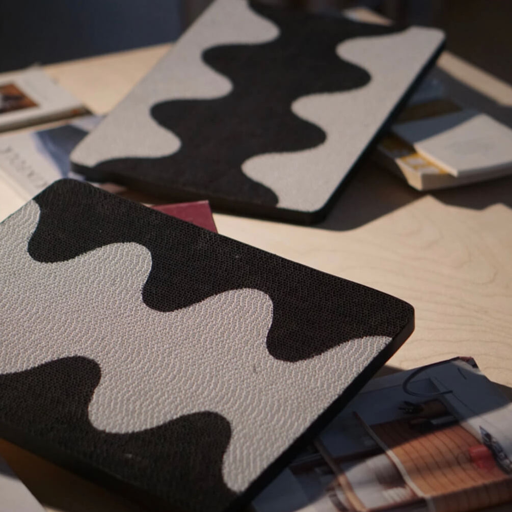 Close-up of two Coral Cat Scratching Pads with modern wave design on tabletop