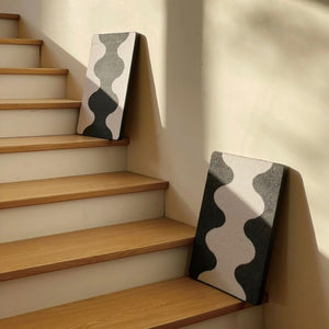 Two Coral Cat Scratching Pads leaning on stairs with minimalist black-and-white wave design
