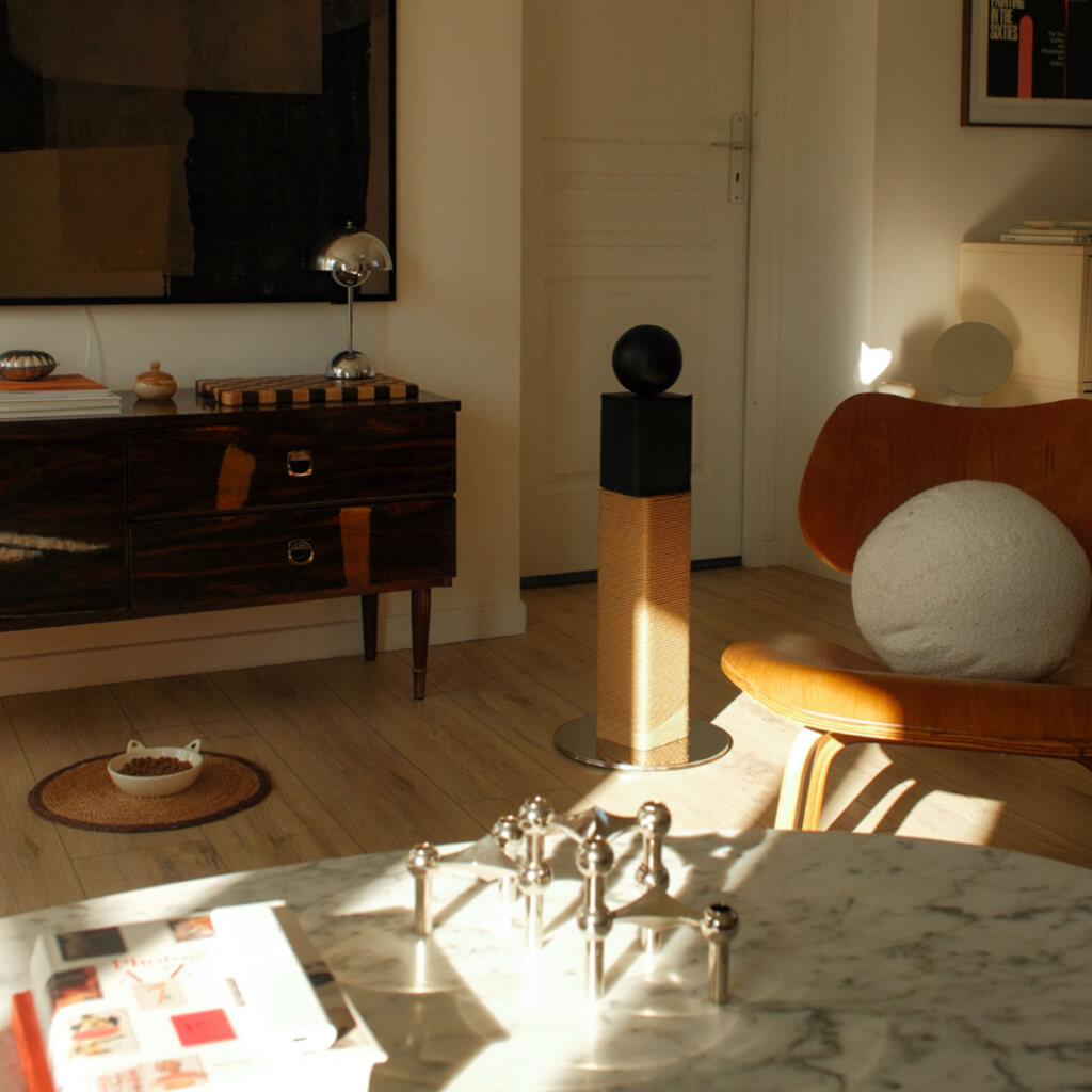Tall two-tone sisal cat scratching post on polished metal base styled in a mid-century modern living room; design-forward pet furniture.