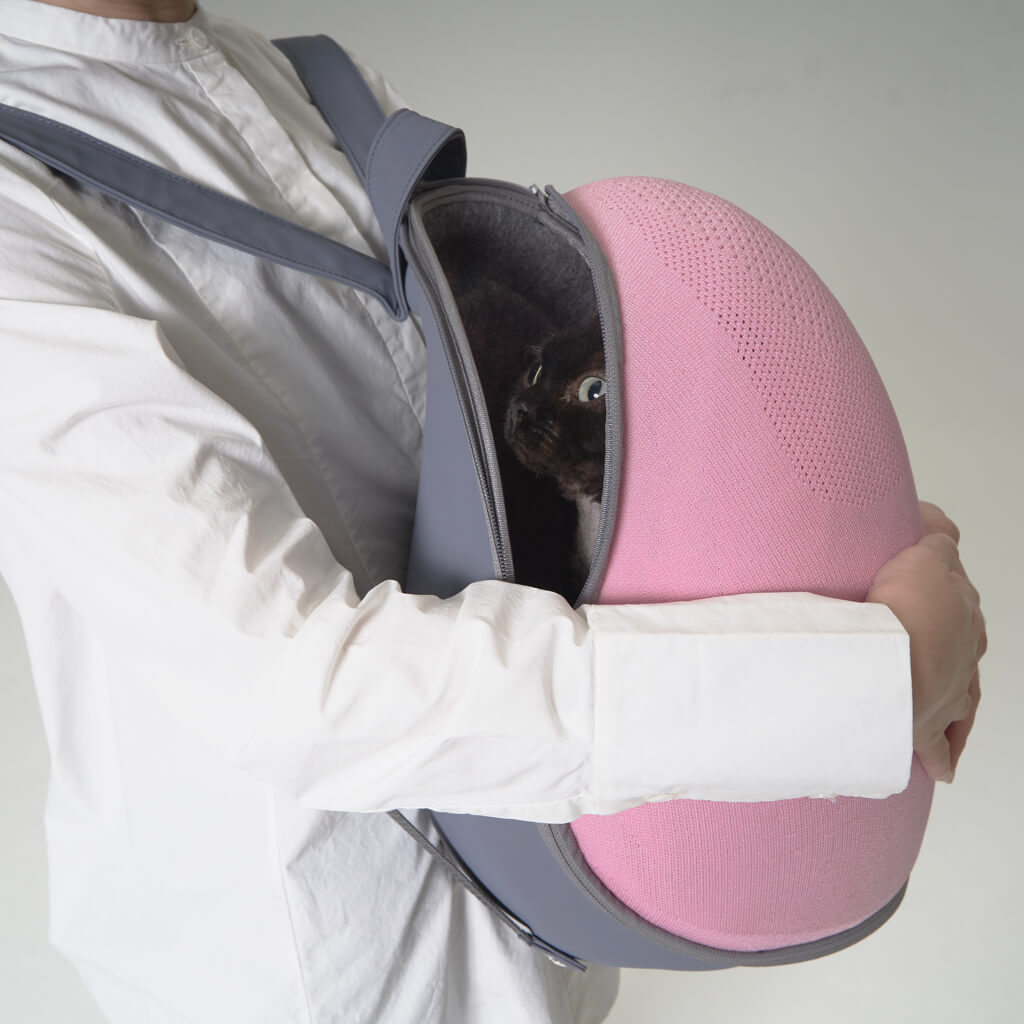 A person carrying a cat inside the Extra-light Cat Travel Backpack, showing the cocoon-like design for cat comfort.
