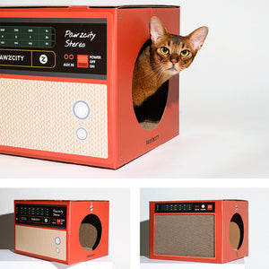 Cat peeking out from the side entrance of the red Retro Speaker Cat House & Scratcher, blending functionality and retro aesthetics.
