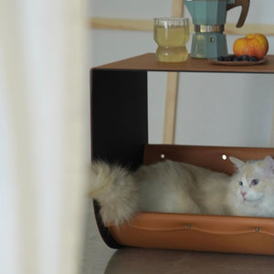 Modern saddle leather cat cave side table with a cozy cat resting inside, blending functionality with luxury home decor.