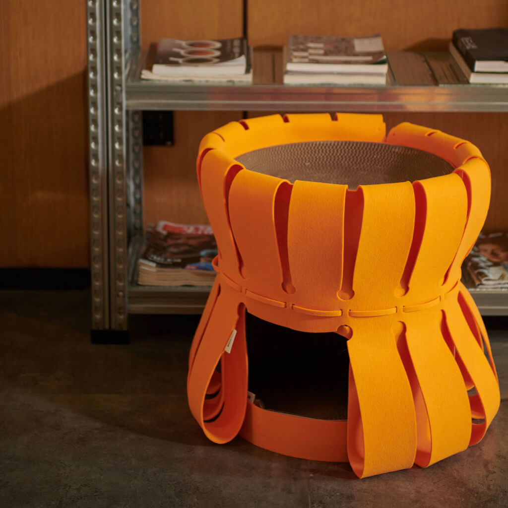 Vibrant orange two-tier Cat Fortress Traveller Den placed in a modern living room setting.