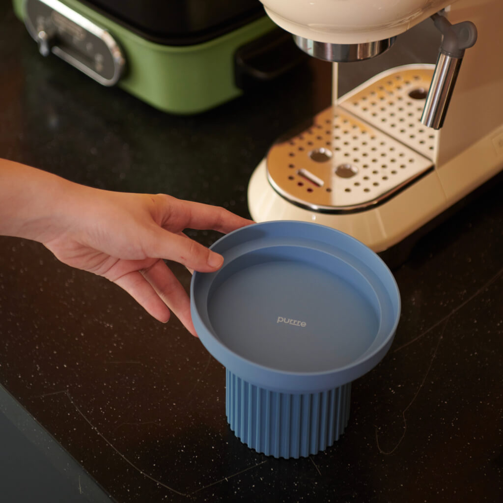 Purrre Teeth Party Pet Bowl - Airy Blue on kitchen counter next to coffee machine.