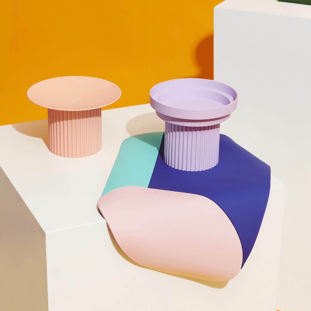 Purrre Teeth Party Pet Bowl - Pale Purple on a Colorful Display - Pale purple pet bowl next to a light pink bowl on a multicolored display.