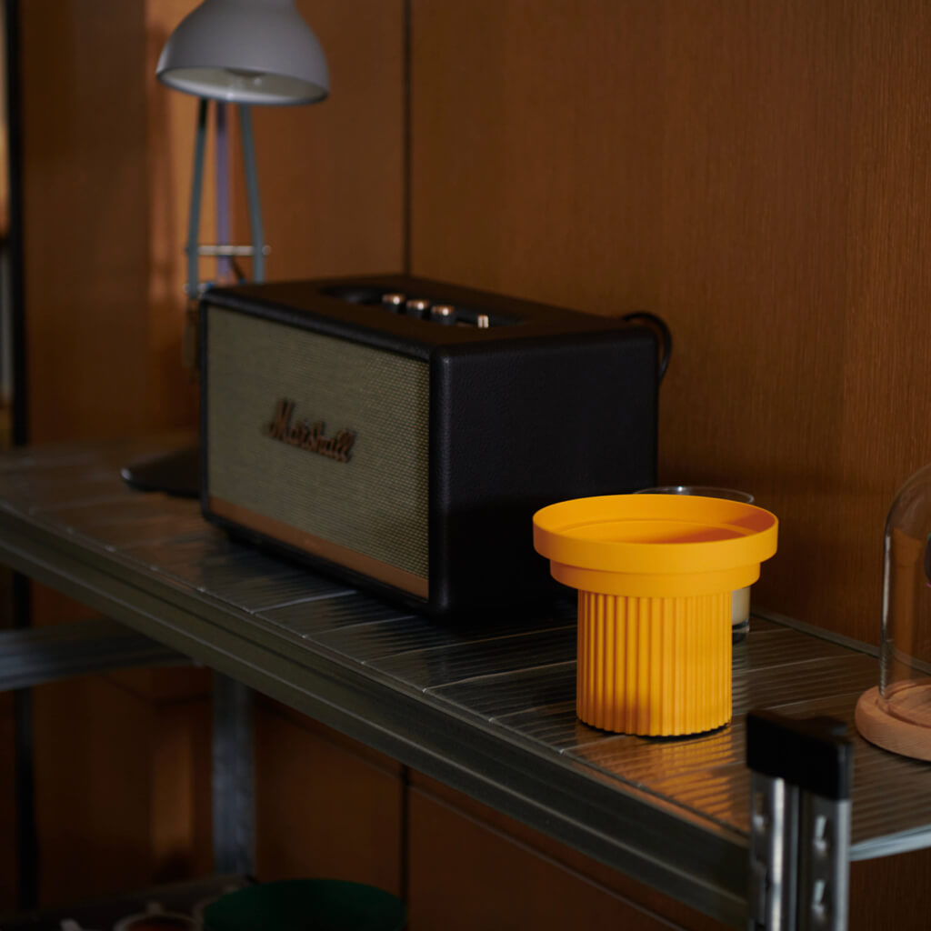Stylish Purrre Sunset Yellow pet bowl next to a vintage speaker, enhancing home décor.