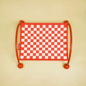 Stylish red cat hammock featuring a vibrant checkerboard pattern on a plain cream background.