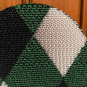 Checker cat scratcher with black and green diamond patterns against a wooden wall.