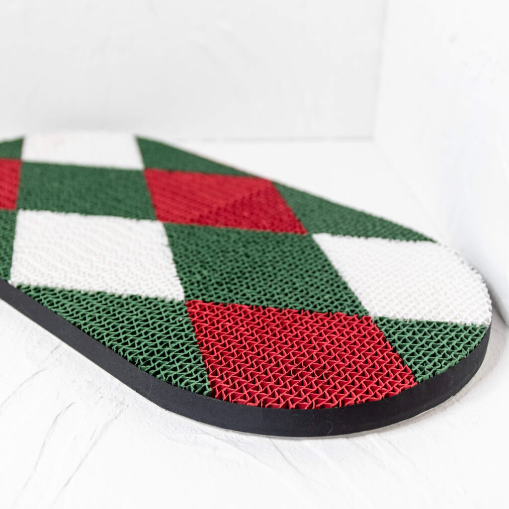Side view of the Checker cat scratcher with red and green diamond patterns on a white wall.