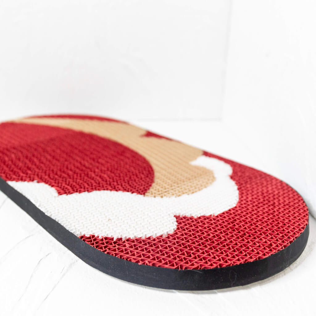 Side view of the Hand-Crafted Paper Art Cat Scratcher in red, white, and beige colors placed on a white surface.