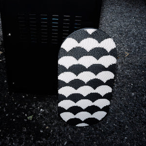 Black and white Koi Fish-inspired cat scratcher displayed outdoors against dark gravel for contrast.