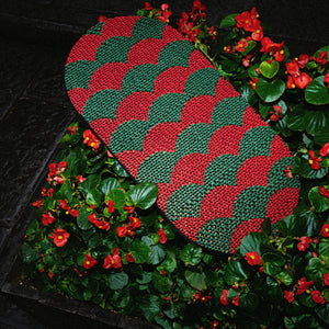 Red and green Koi Fish-inspired cat scratcher surrounded by vibrant garden flowers.