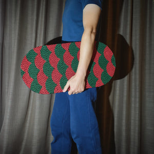 A man holding the red and green Koi Fish-inspired cat scratcher for a size reference.