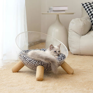 White cat sleeping on blue patterned cushion inside transparent Moonlight Nest bed