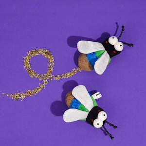 Catnip-filled plush bug toys with natural dried catnip scattered around on a purple surface.