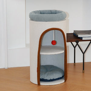 Chic round cat tower with dual sleeping zones and stylish red toy ball, placed near reading nook.