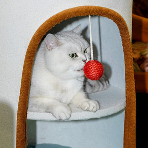 White cat sitting inside cylindrical cat condo with trendy fabric and top bolster bed.