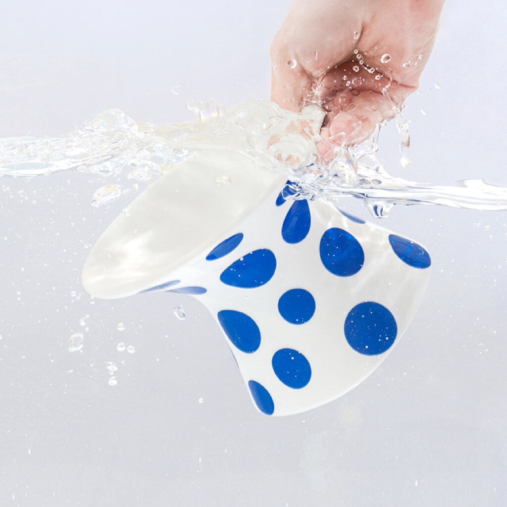 Close-up of a hand cleaning the ZEZE Blue Polka Dot Ceramic Bowl underwater.