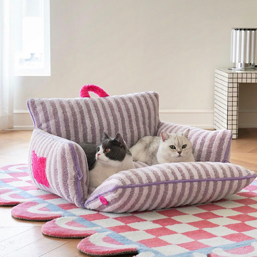 Two cats lounging in purple striped plush cat bed with removable cushion.