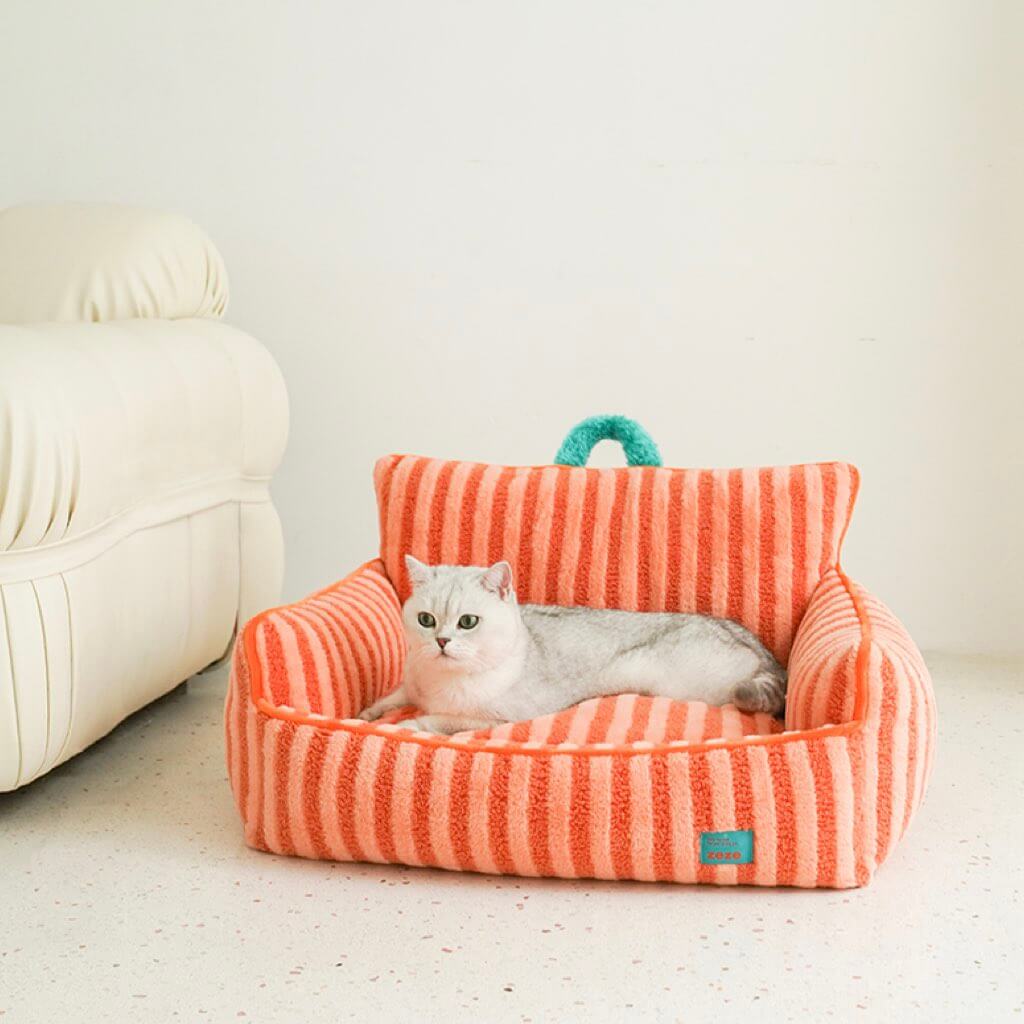 Cat relaxing in orange striped plush cat bed with cushioned sides.