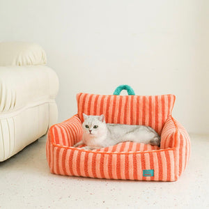 Cat relaxing in orange striped plush cat bed with cushioned sides.
