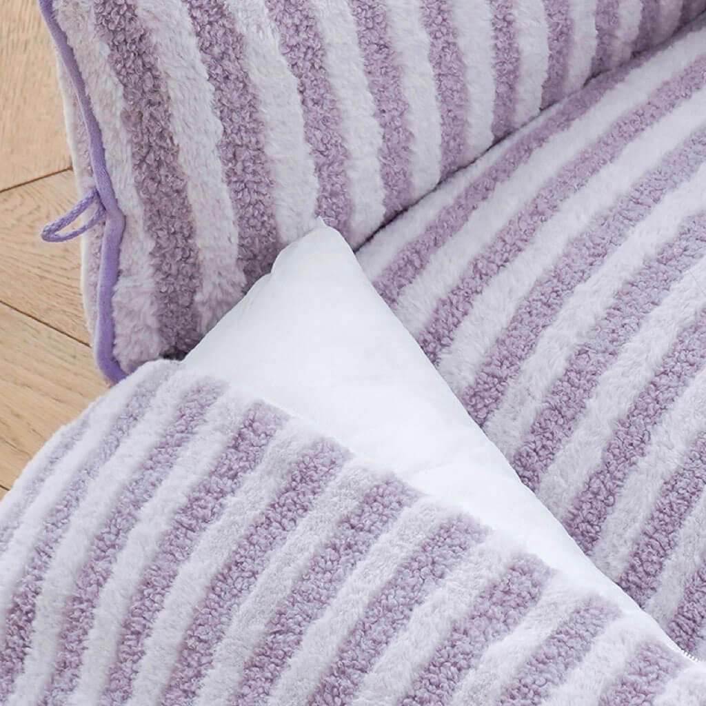 Close-up of removable cushion in purple striped plush cat bed.
